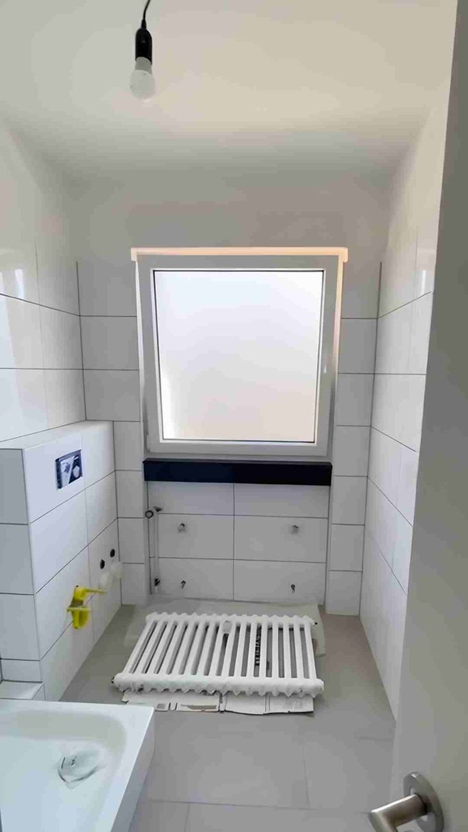 Heller Raum mit Fenster, Heizkörper und weißen Fliesen an Wänden.