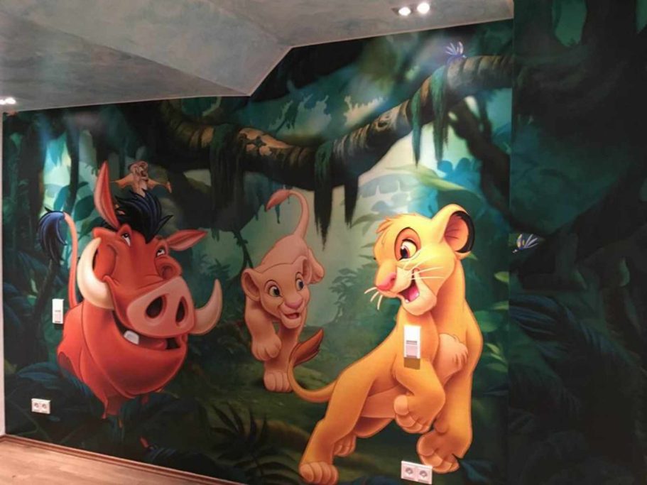 Wandmalerei mit Simba, Timon und Pumbaa in einem dichten, grünen Dschungel.