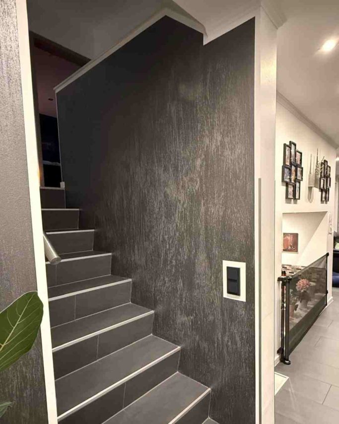 Dunkle Wendeltreppe mit modernem Wanddesign und Dekoration im Hintergrund.