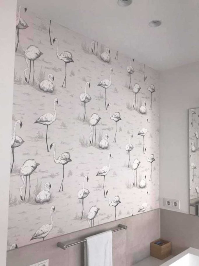 Helle Wand mit fliederfarbenem Flamingo-Tapetenmuster in einem Badezimmer.