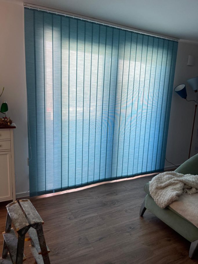 Transparente Vorhänge in Blau vor einem Fenster, helles Holzfußboden, gemütliche Ecke.