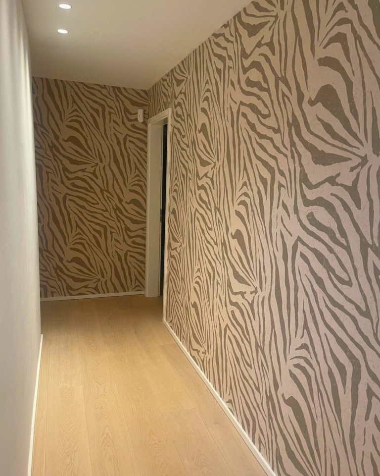 Tapete im Zebramuster. Ein schmaler Flur mit Zebra-Muster-Tapete und hellem Holzfußboden. Tapeziert von Raumgestaltung Breuer in Köln.