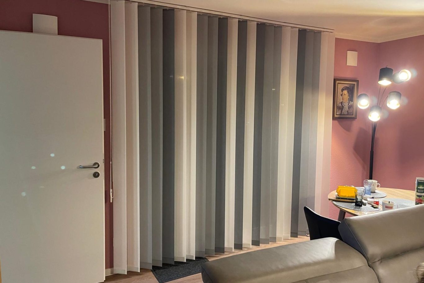 Wohnraum in Köln mit neuen Jalousien Ein Raum mit vertikalen Jalousien, einem Tisch und einem modernen Licht.